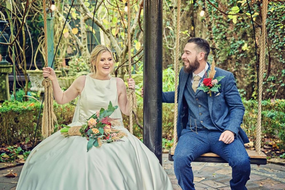 The wedding couple sat on wooden swings